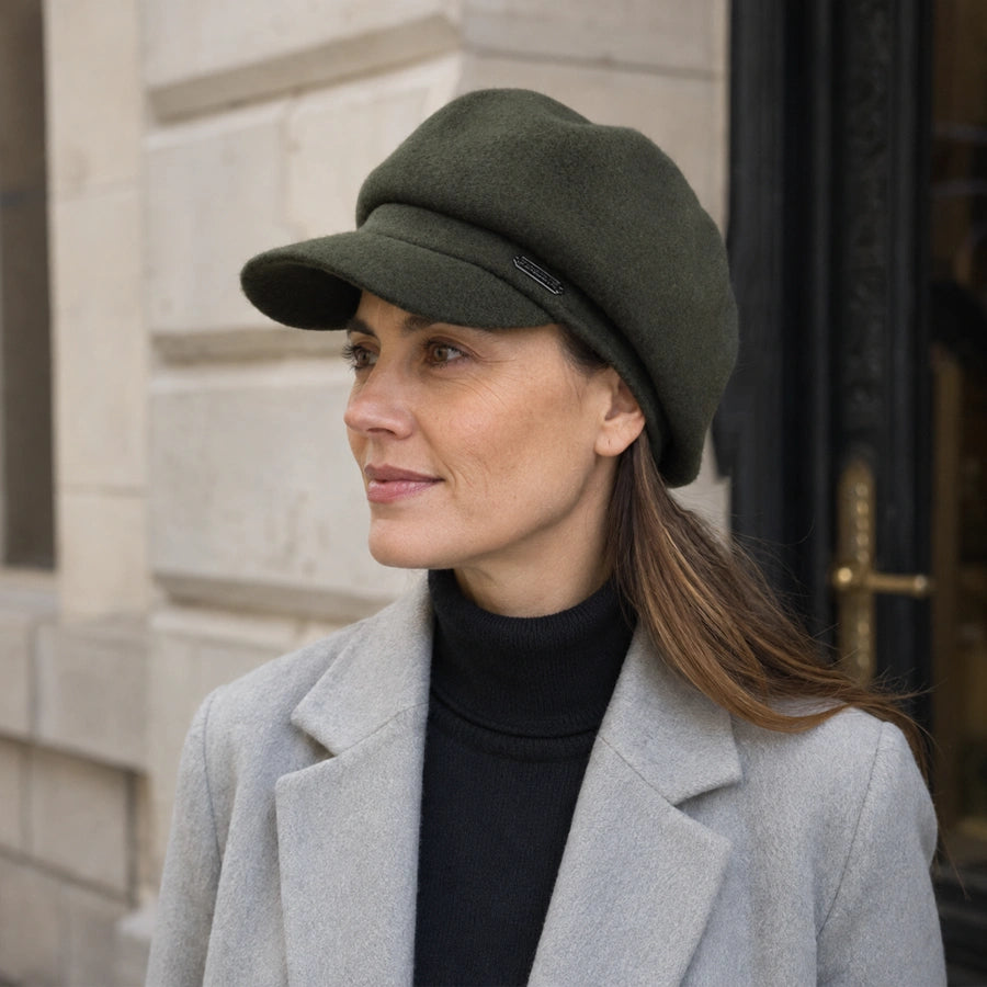 Woman wearing an olive green wool newsboy cap with a winter coat