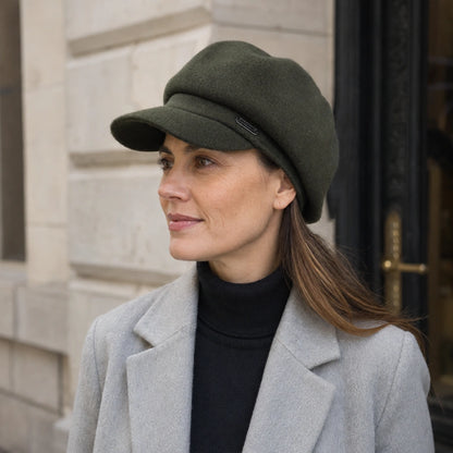 Woman wearing an olive green wool newsboy cap with a winter coat