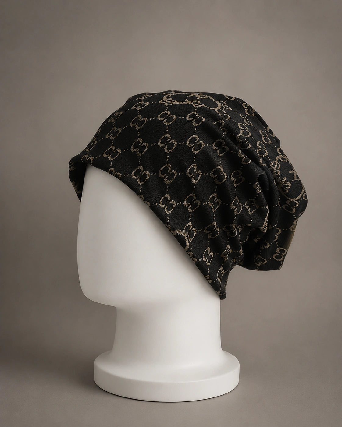 Side profile view of oversized black beanie hat featuring soft knit construction, baggy slouch design and jacquard double C pattern.