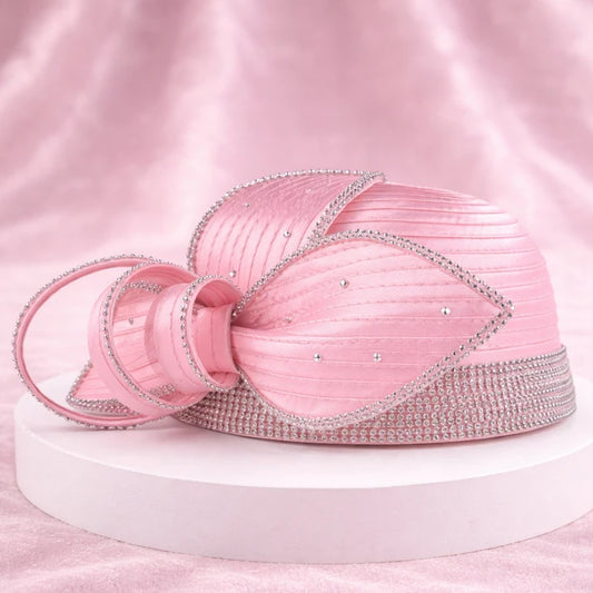 Close-up of a pink satin church hat with floral design and sparkling crystals, ideal for weddings.