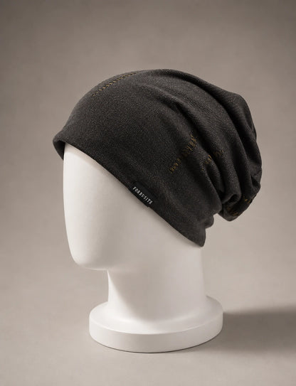 Premium bronze black slouchy beanie displayed on mannequin with soft luxury lighting and minimalist neutral background
