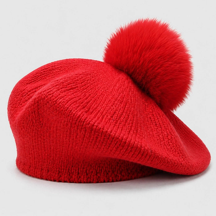 Red beret with a fluffy pom-pom for winter fashion. Soft knitted fabric, stylish and cozy.