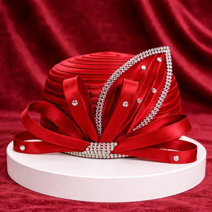 Stunning red satin church hat adorned with rhinestones and intricate ribbon details, elegantly placed on a white base with a matching red velvet backdrop.