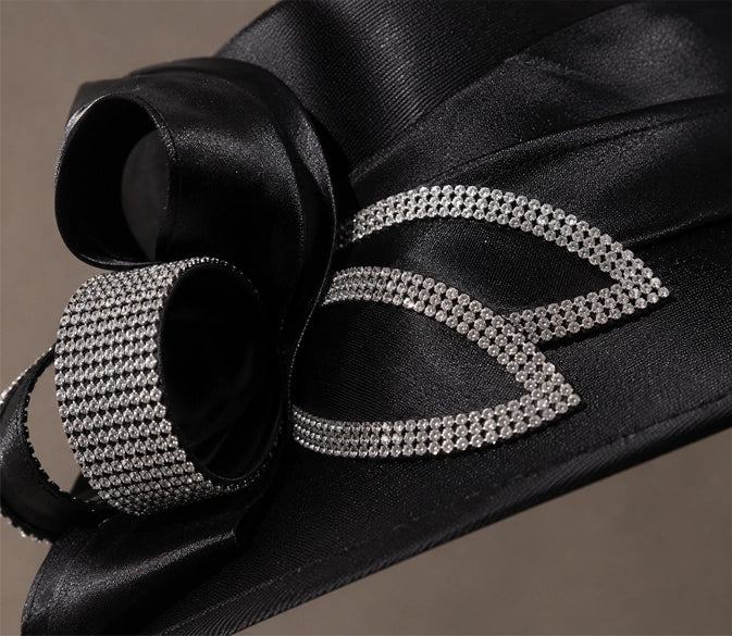 Close up detail of rhinestone embellishment and satin texture on luxury black church hat