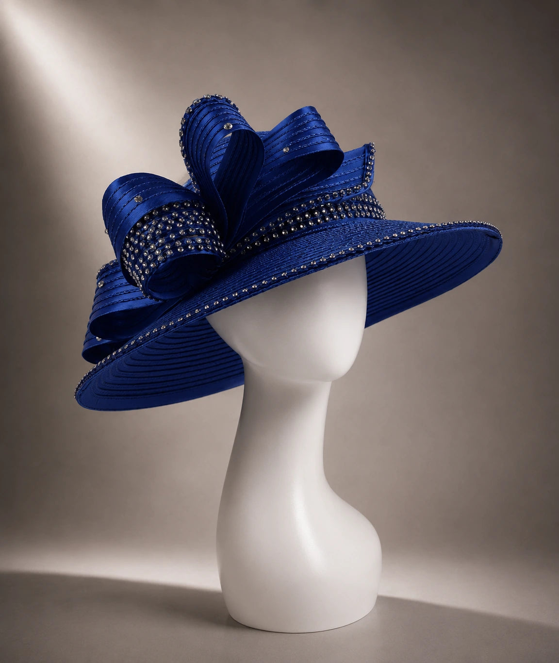 Royal blue wide brim church hat displayed on mannequin featuring elegant bow accents and sparkling rhinestone embellishments.