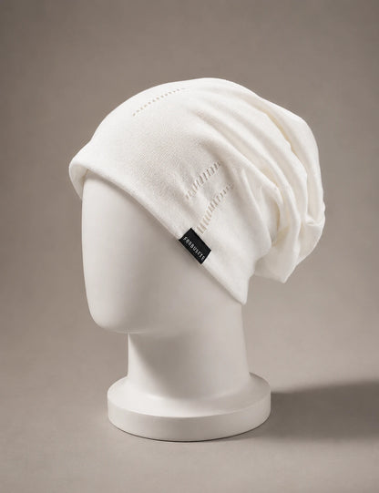 White slouchy knit beanie in minimalist style displayed on mannequin with soft neutral luxury background