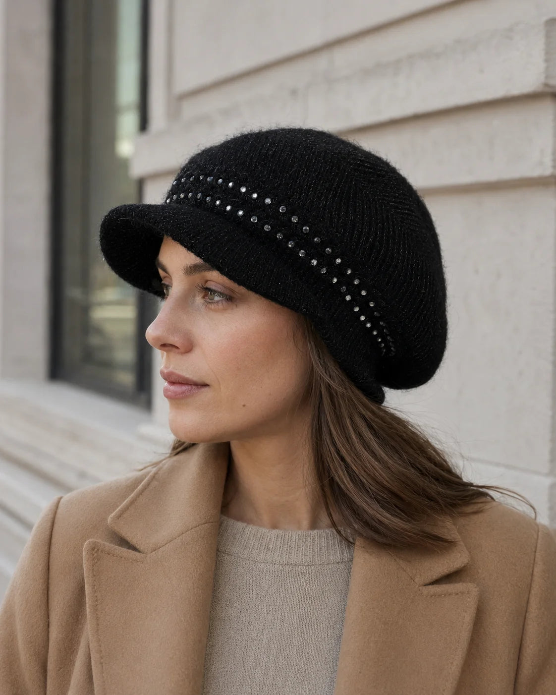 Woman wearing a black sequin knit visor beanie with a camel coat outdoors
