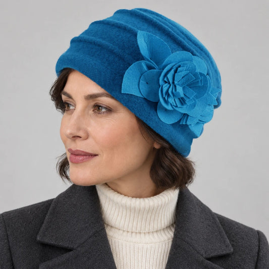 Woman wearing a bright blue brimless boiled wool hat with fixed flower detail