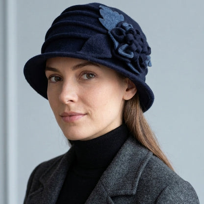 Woman wearing a navy wool felt cloche hat with a ruched crown and floral side detail