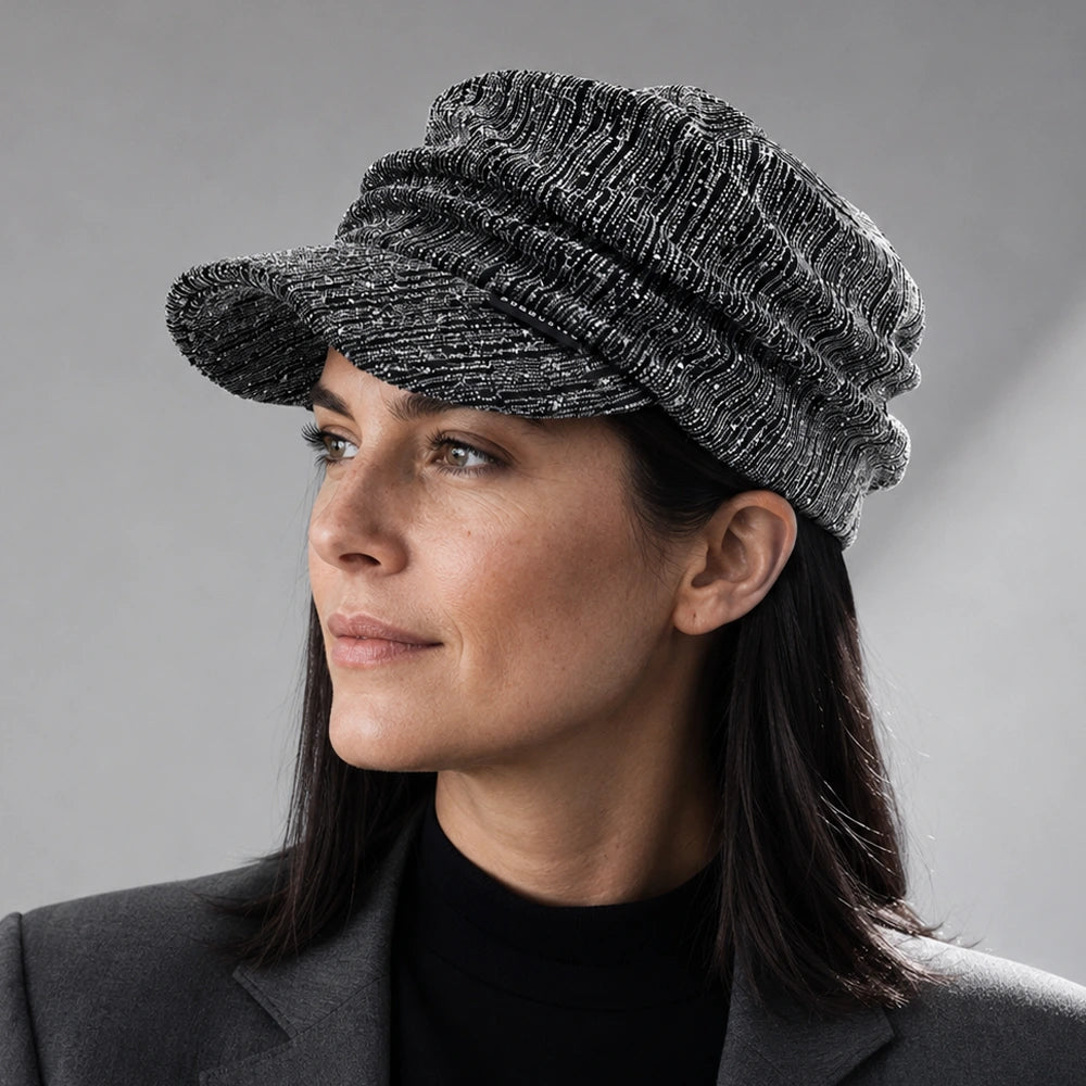 Woman wearing a black and silver ruched visor cap with satin lining and rhinestone detail
