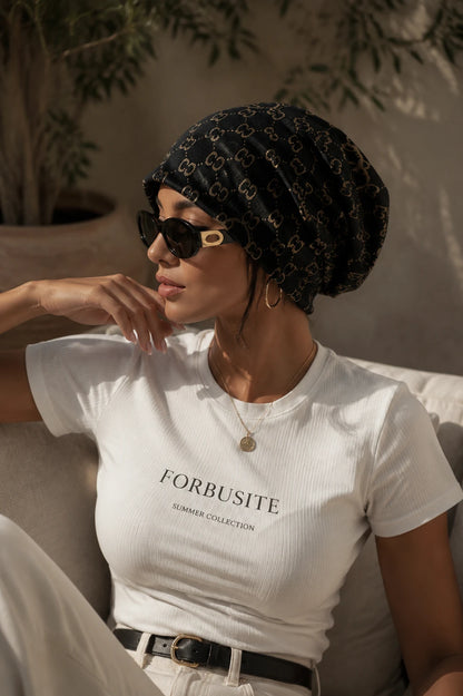 Woman wearing a black slouchy beanie hat with jacquard CC print, lightweight all-season knit design, casual summer lifestyle fashion.