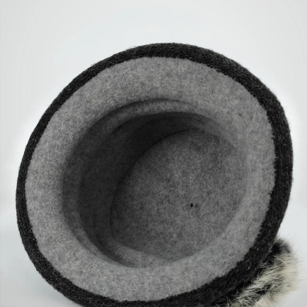Close-up of the fixed leaf-shaped detail and fuzzy pom on a gray cloche hat